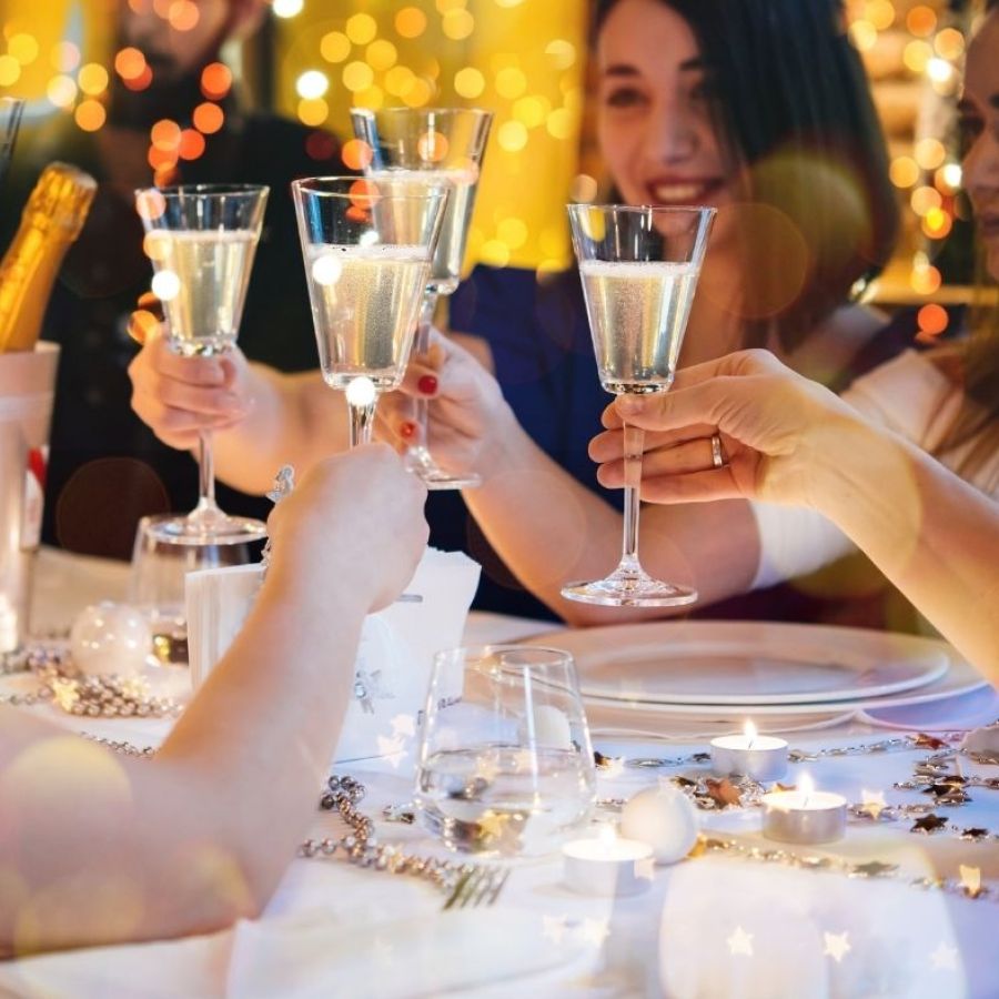 A picture of a table of people chinking Champagne and celebrating a Christmas party
