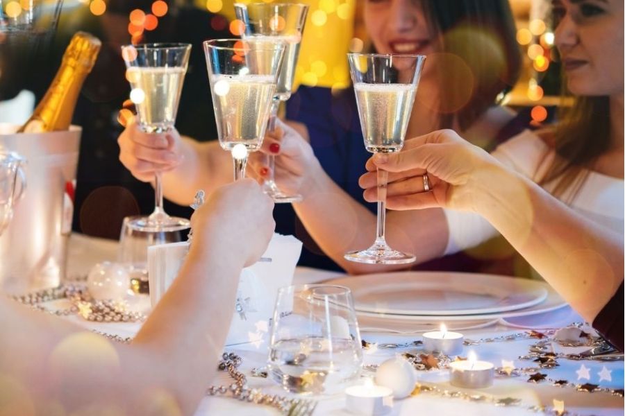 A picture of a table of people chinking Champagne and celebrating a Christmas party